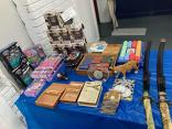 Photo of vendor table displaying miscellaneous toys, knives, swords, and collectables for sale.